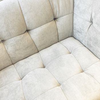 Corner of a shiny white velvet sofa. Classic style expensive furniture.