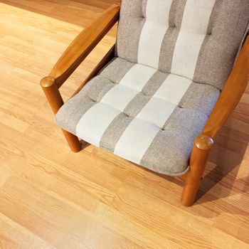 Comfortable striped armchair on a wooden floor. Modern furniture with retro feel.