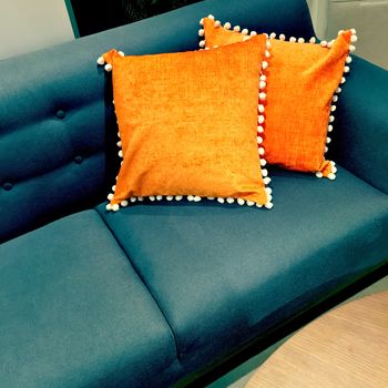 Fancy orange cushions decorating a sofa. Luxurious furniture.