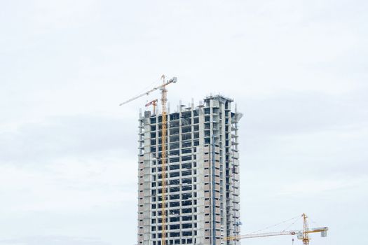 Several cranes are building a building with a white background.