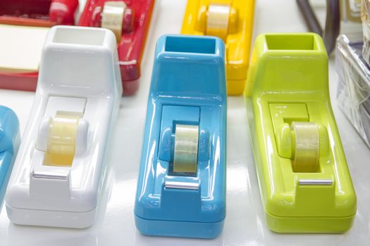 3 multi-colored tape dispensers placed on a white desk