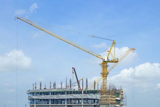 Crane lifts building with construction workers.