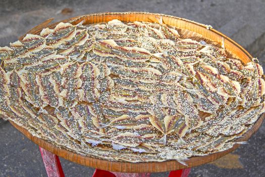 Dried fish sprinkle white sesame on a sieve.