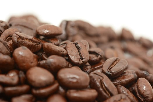 Macro of a pile of roasted coffee beans, on a white background