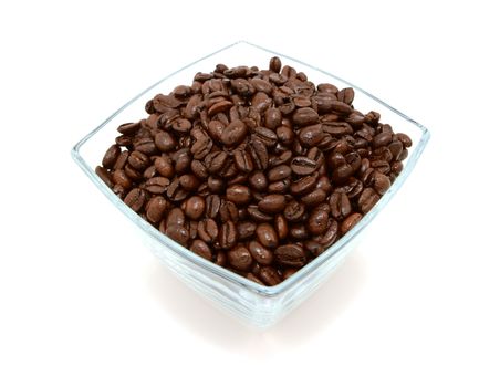 Glass bowl filled to the brim with dark roasted coffee beans, on a white background
