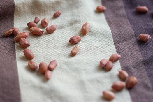 Peanuts in a peel on a brown fabric