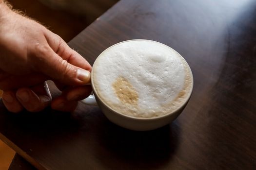 Close up view of the hand of a man working in a coffee house preparing espresso coffee waiting for the coffee machine to finish pouring the fresh beverage into two small cups.