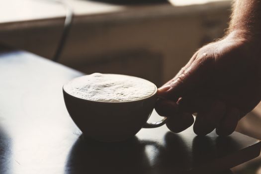 Close up view of the hand of a man working in a coffee house preparing espresso coffee waiting for the coffee machine to finish pouring the fresh beverage into two small cups.