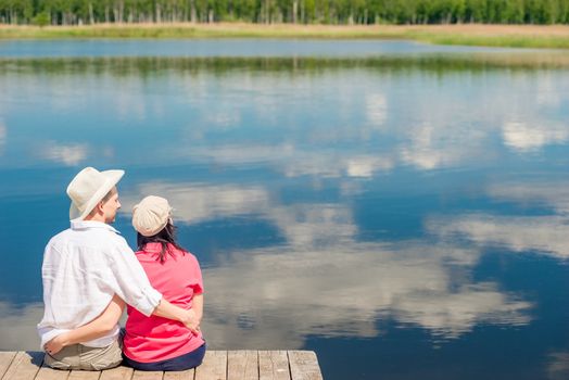 happy couple hugging, view from behind in the background of a beautiful scenic lake