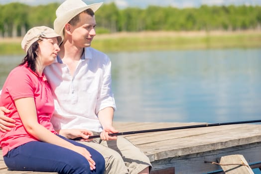 Barefoot happy couple on the pier to catch a fish on a beautiful lake