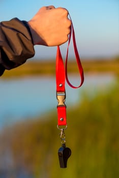 close-up of a whistle on a lace in a male hand in the fresh air