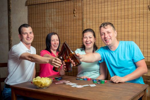cheerful friends drink beer for card game indoors