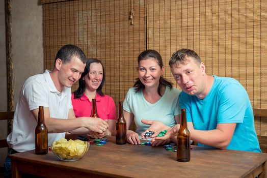 friends while playing poker, people at the table with beer and cards