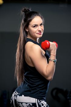 Vertical close-up portrait woman with dumbbells in the gym