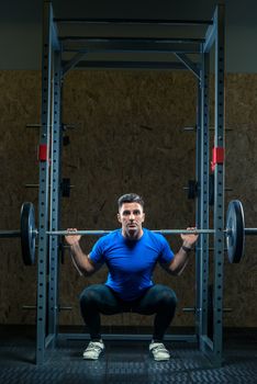 strong young bodybuilder with a barbell in the gym is practicing