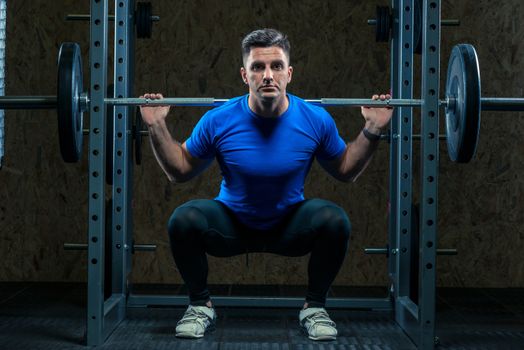 cute young bodybuilder with a barbell in the gym is practicing