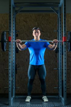 portrait of a young strong athlete at the gym in the gym with a barbell