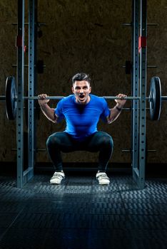 strong man with a barbell makes an effort in the gym, a bodybuilder in training