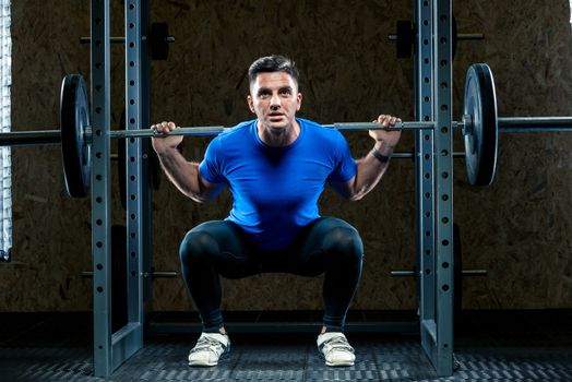 horizontal portrait of an athlete with a barbell makes an effort in the gym, a bodybuilder in training