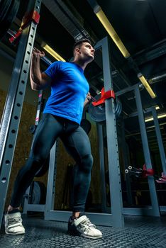 strong athlete in training in the gym, a man raises a heavy barbell