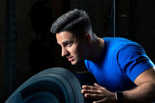 close-up portrait of an athlete exercising with a wheel in the gym