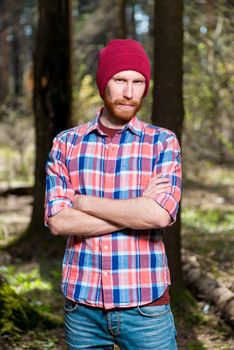 portrait of a man with a beard in a plaid shirt and hat in the woods