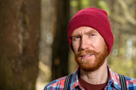 portrait of a hipster with a red beard close-up in the forest