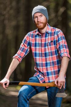 portrait of a man in a plaid shirt with an ax in the forest