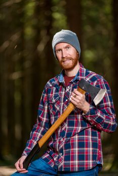 angry forester with a grin with an ax in his hands in the woods