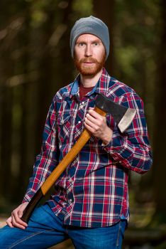 Bearded woodcutter with ax posing in forest