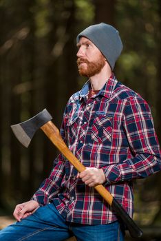 vertical portrait of a lumberjack with an ax in the summer forest