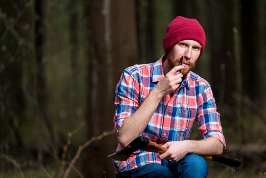 a forester with an ax in the forest combs his beard