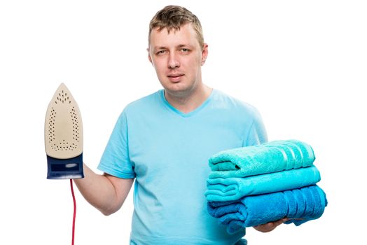 portrait on white background man with iron and a pile of ironed towels isolated