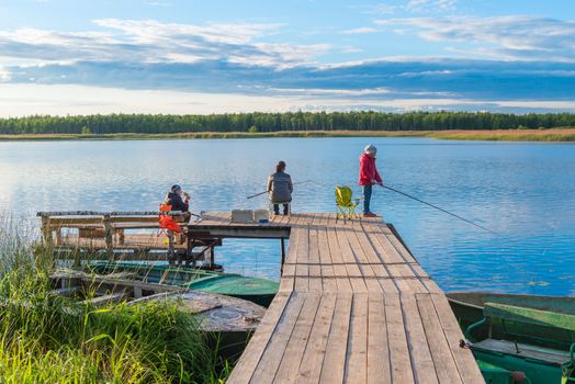 family on a fishing trip on a pier in the background of a picturesque lake