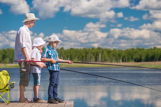 on a wooden pier the father teaches his sons to fish properly