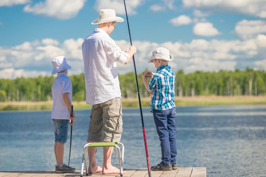 a man's hobby - a father with his sons on fishing in good weather on the lake