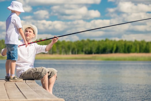 fishermen father and son on the pier fish in the lake