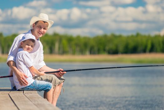 happy men with a fishing rod on a wooden pier while fishing