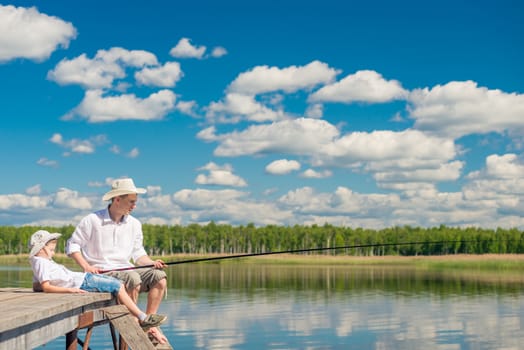 relaxed boy with his father on a fishing trip on a beautiful lake