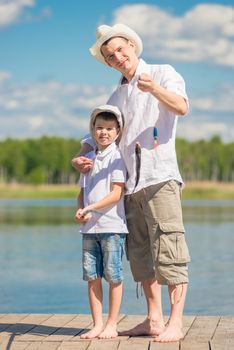 happy fishermen on the pier with a big fish on the hook, fishing on the lake