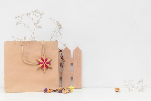 Composition of paper bag, dried flowers and decoration on white cracked wall background.