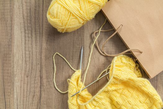 Light yellow knitting wool and knitting needles on wooden background. Top view.copy space. Knitted fabric and yarn on a wooden surface.