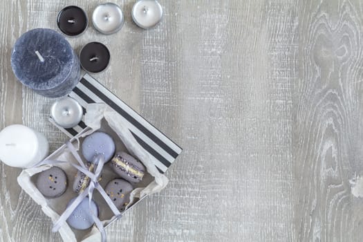 Blue and gray macaroon, decor and many different candles on light wooden surface. Beautiful romantic background with blue and gray colors Wedding, birthday, easter, mother day, valentine day composition