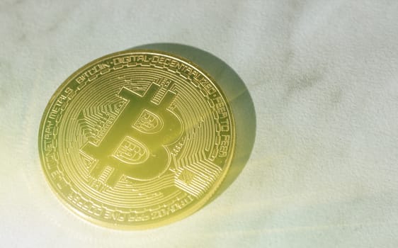 One Bitcoin coin closeup in sunlight with shadow