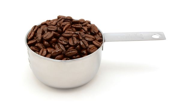 Roasted coffee beans in an American cup measure, on a white background