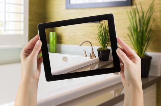 Female Hands Holding Computer Tablet In Bathroom with Photo on Screen.