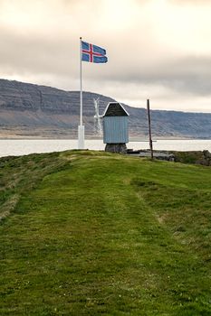 Windmill and Icelandic flag in Vigur island in a cloudy and windy day, Iceland