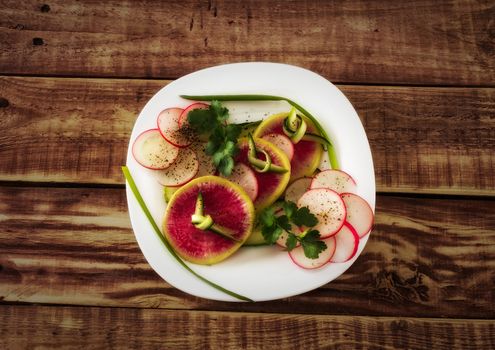 Still-life with vegetable salad with radish, cucumber, green onion and greens