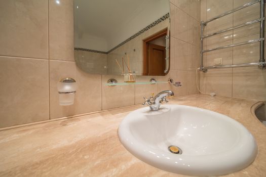 Close up of modern faucet and ceramic sink in bathroom