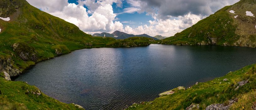 panorama of Capra lake, Romania. gorgeous landscape of Fagarasan mountains on a cloudy summer day